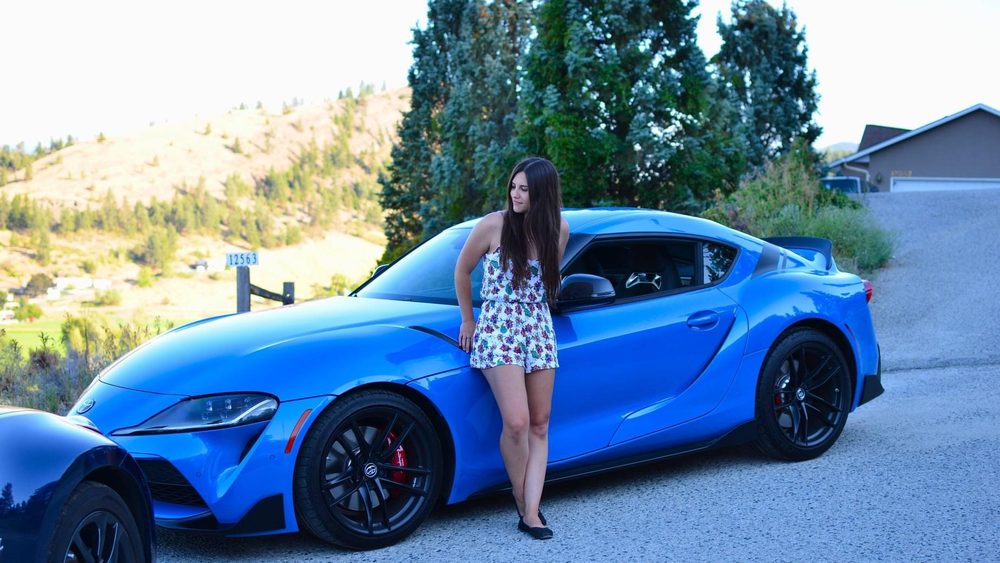 Dr. Maia standing beside a blue sports car